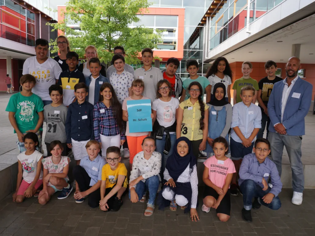 Klassenfoto einer neuen fünften Klasse vor der roten Wand.